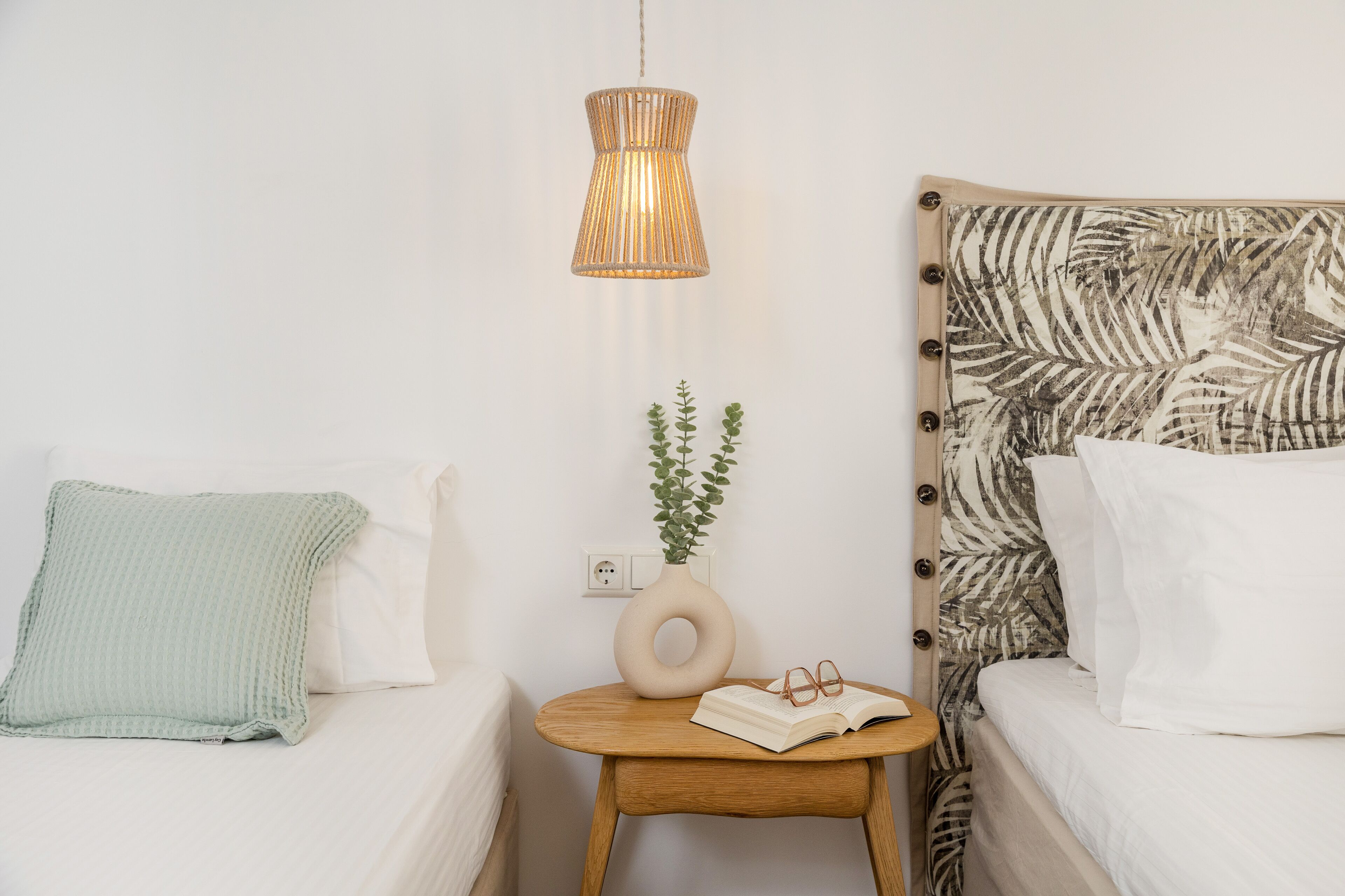 A neatly arranged bedroom with a bed, bedside table, and a hanging light fixture.