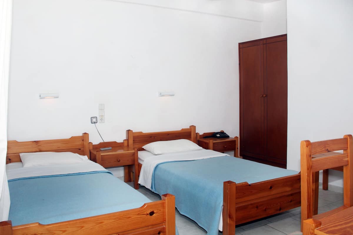 A room with two wooden beds, a wardrobe, and a nightstand with a phone.