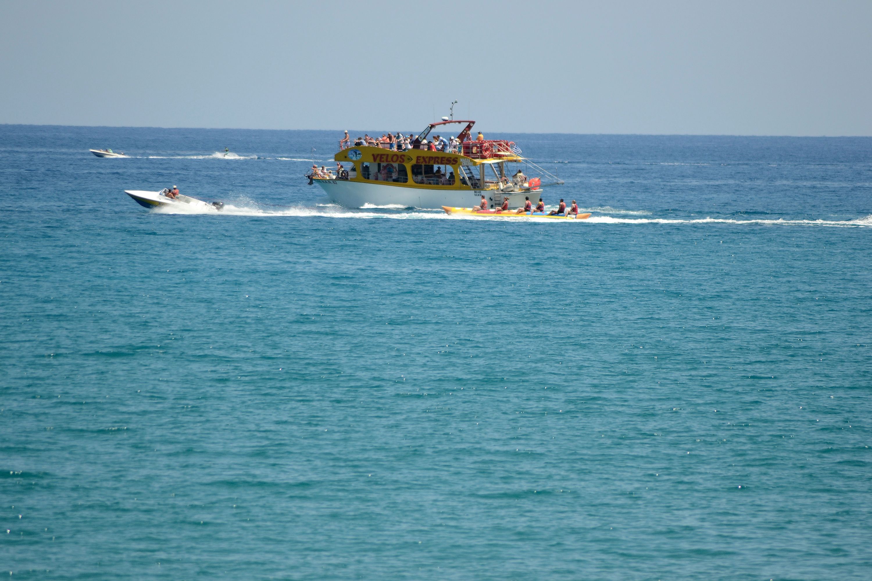 A large yellow and white boat with passengers, moving through a calm sea.
