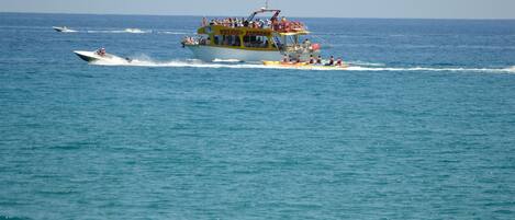 A large yellow and white boat with passengers, moving through a calm sea.