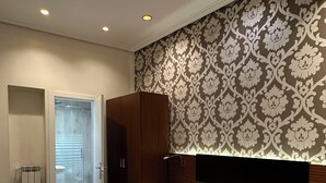 A hotel room with two beds, a wardrobe, a bathroom with a glass door, and a patterned wall. - Hostal Atocha Almudena Martin (Madrid)