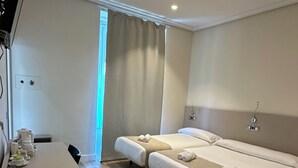 A hotel room with two beds, a desk, and a bathroom. - Hostal Atocha Almudena Martin (Madrid)