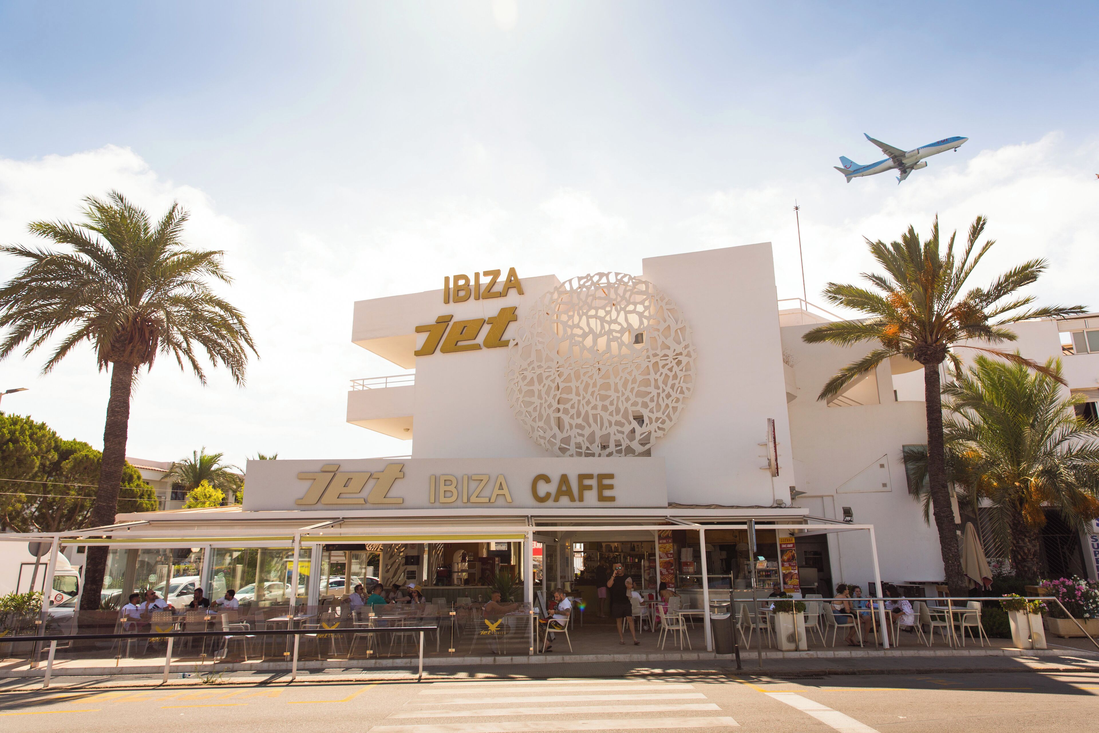 The exterior of Ibiza Jet Cafe with outdoor seating and palm trees.