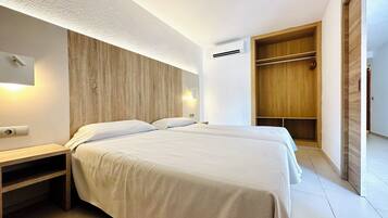 Een moderne slaapkamer met een groot bed, nachtkastjes, een kledingkast en een airconditioning.