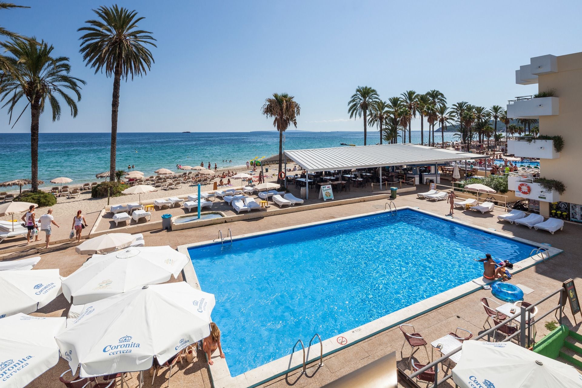 A resort pool area with lounge chairs, umbrellas, and a bar.