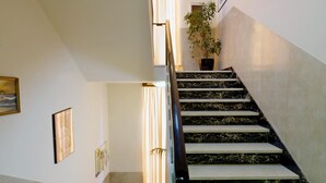 Un escalier avec une rampe, un pot de fleurs et des tableaux encadrés accrochés aux murs.