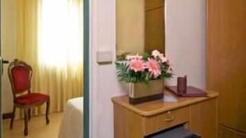 Ett hotellrum med ett skrivbord i trä, ett litet kylskåp, en spegel och en stol.