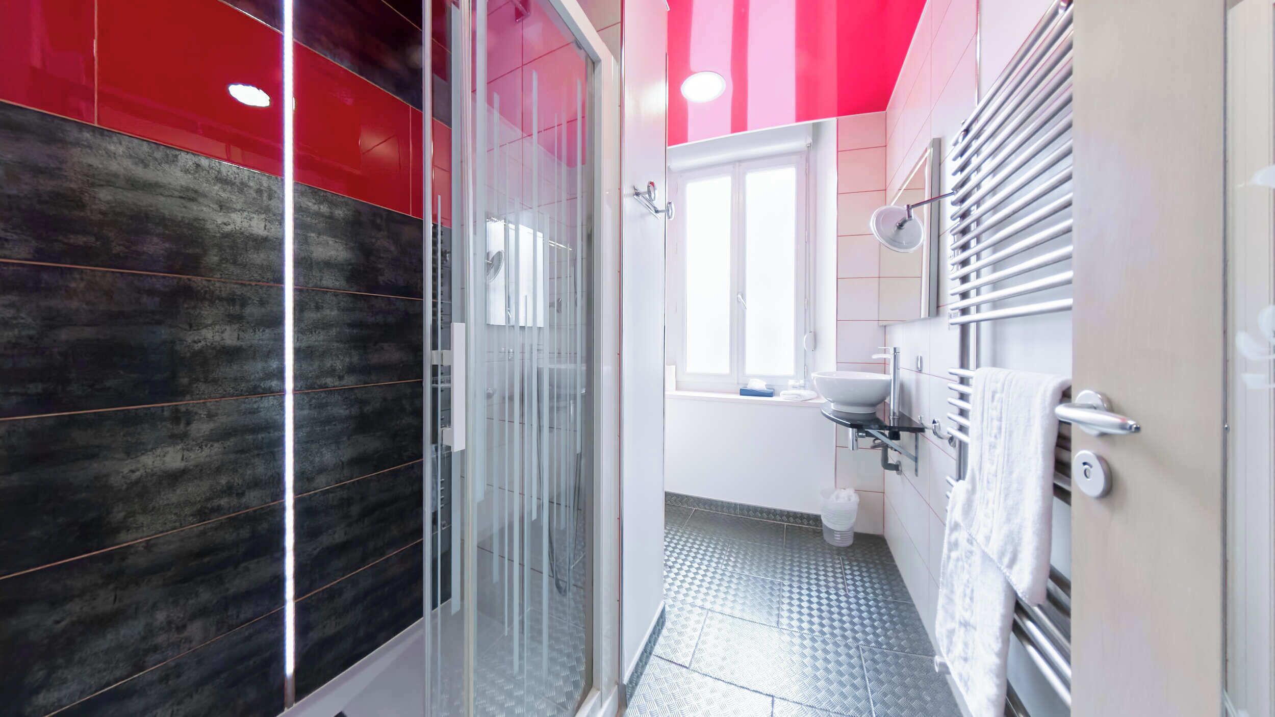 Un baño moderno con cabina de ducha de vidrio, un lavabo blanco y un perchero para toallas.