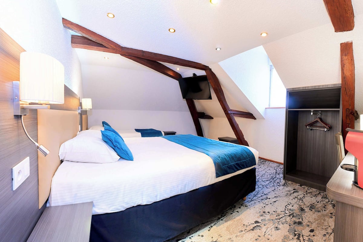 A bedroom with a bed, a bedside table, a TV mounted on the wall, and a wardrobe.
