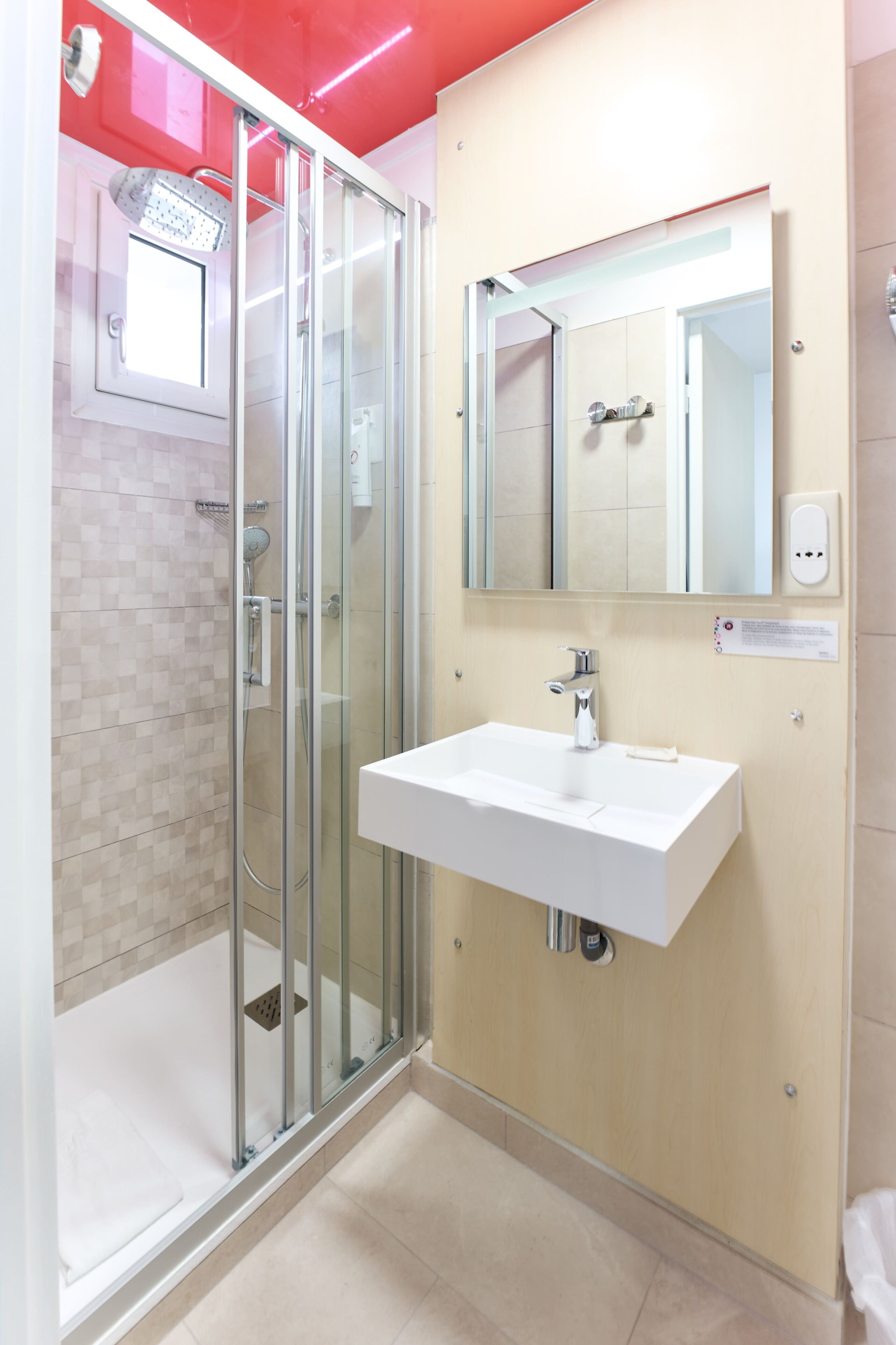 A modern bathroom with a glass shower enclosure, a white sink, and a mirror above it.