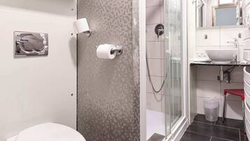 A modern bathroom with a toilet, a glass shower enclosure, a sink, and a mirror.