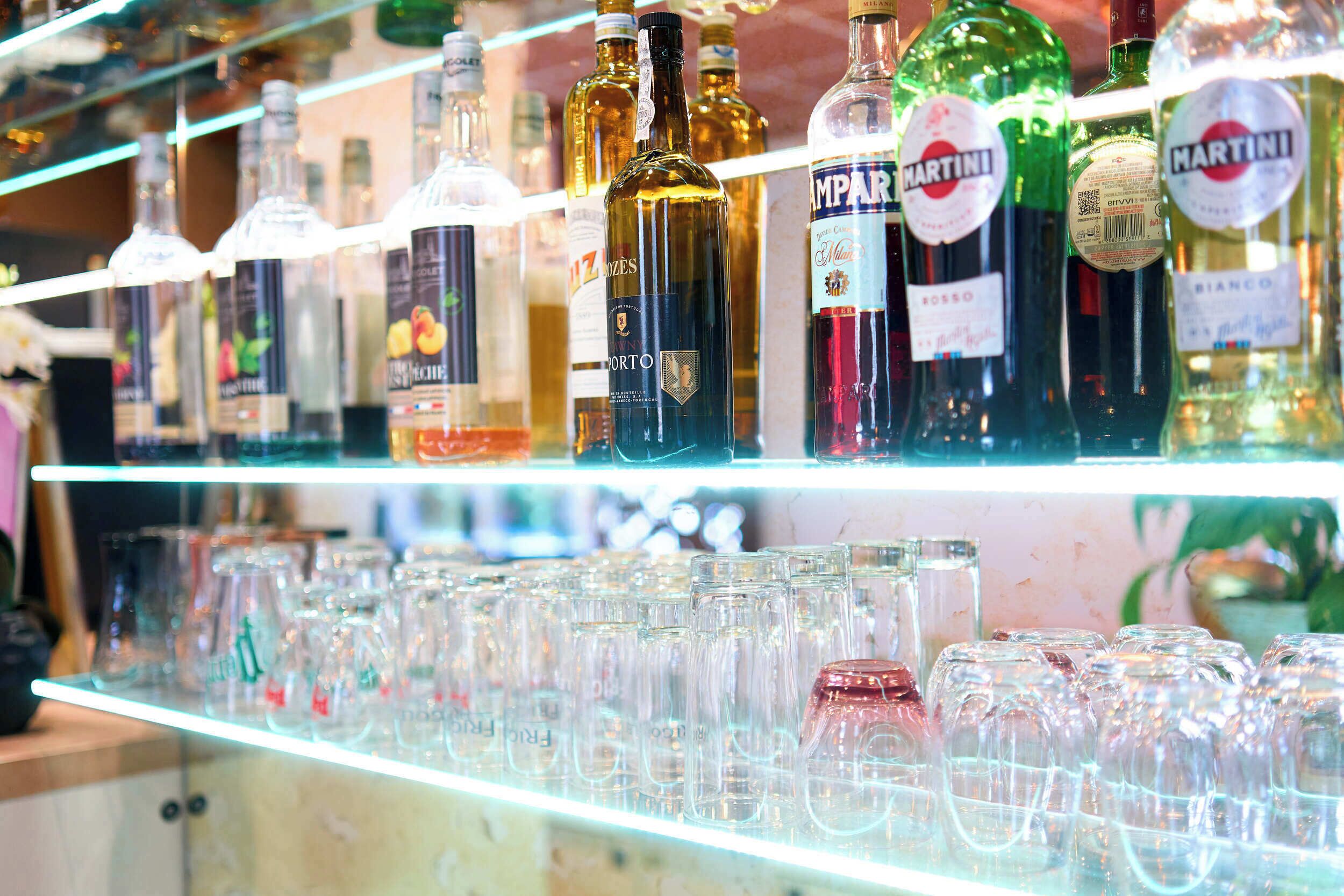 Shelves stocked with various liquor bottles and empty glassware.