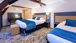 Ein Hotelzimmer mit zwei Betten, einem Schreibtisch und einer Küchenzeile.