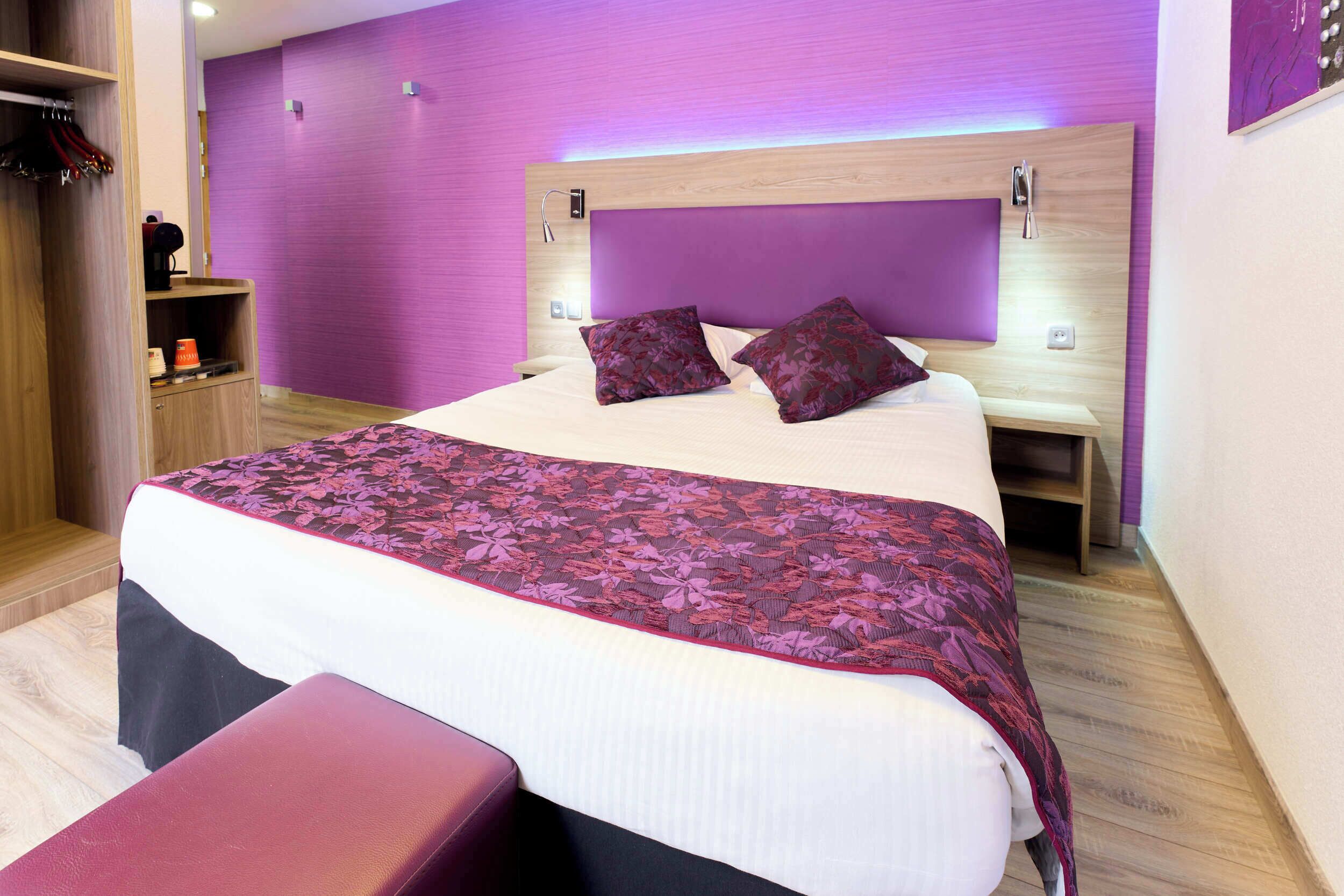 Un dormitorio moderno con una cama grande, un cabecero de madera y una pared morada.