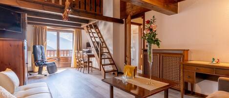 Una sala de estar acogedora con un sofá, una mesa de madera y una escalera que lleva a un balcón.