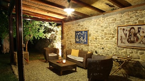 An outdoor seating area with wicker furniture, a stone wall, and a thatched roof.