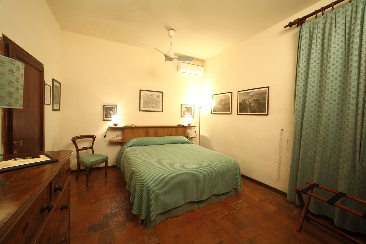 A bedroom with a bed, a chair, a dresser, and a ceiling fan.