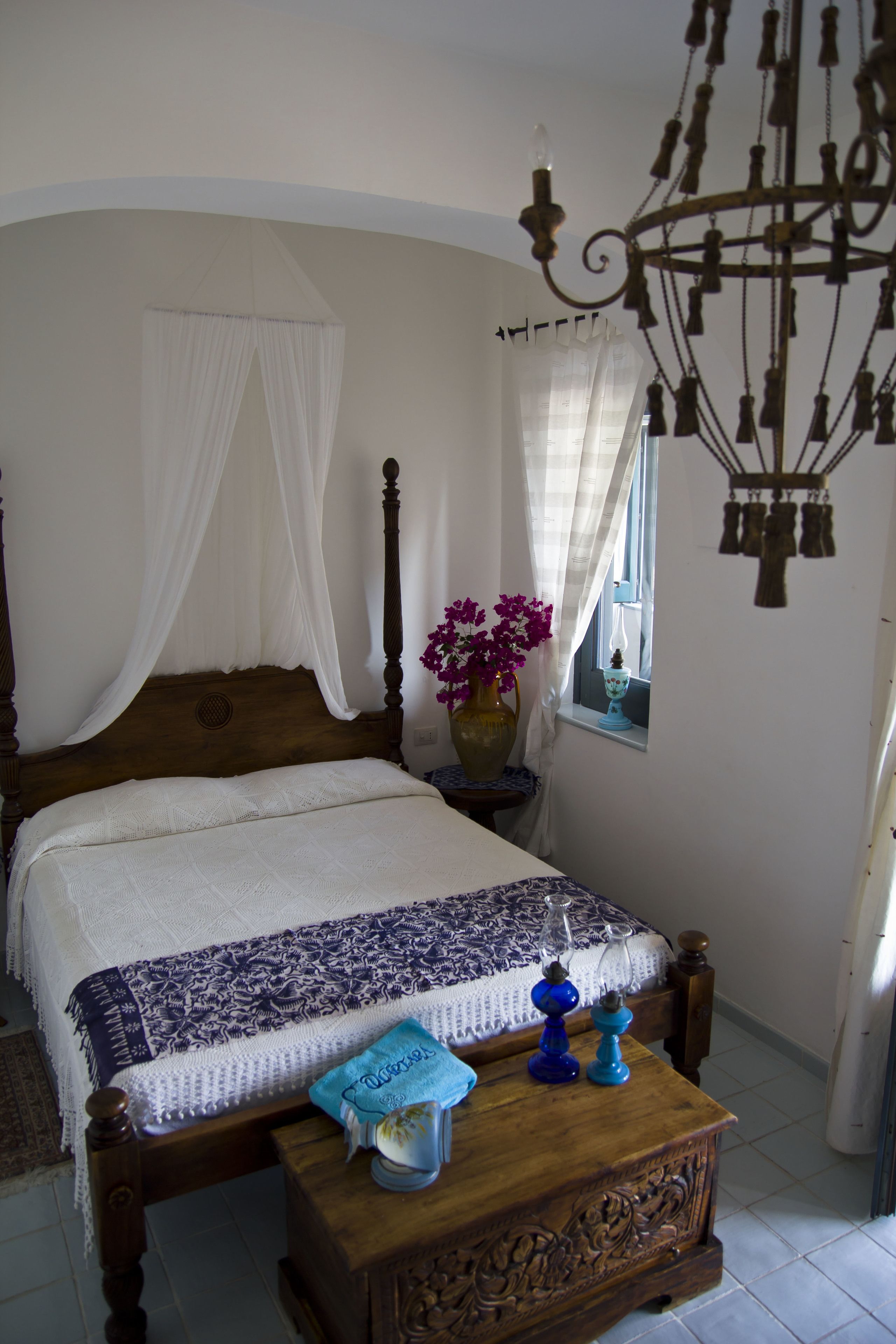 Une chambre à coucher avec un lit en bois, une table de chevet, un vase de fleurs et un lustre.