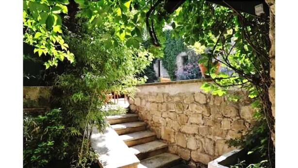 Una escalera de piedra que conduce a un espacio cubierto rodeado de abundante vegetación.
