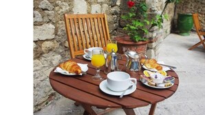 Una mesa de madera dispuesta con artículos para el desayuno, como cruasanes, jugo de naranja y pastelería.