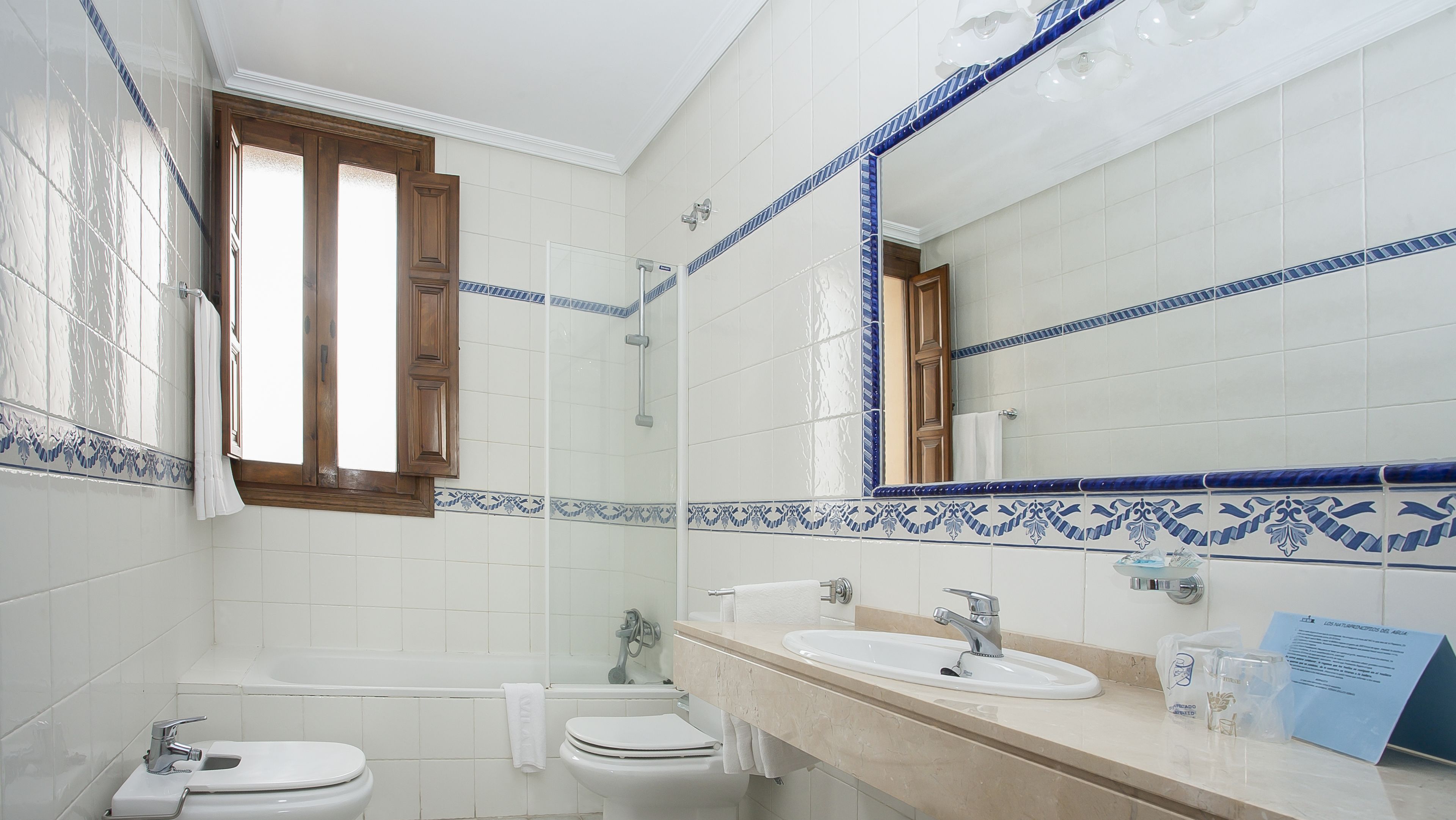 Ein Badezimmer mit zwei Toiletten, einer Badewanne, einem Waschbecken und einem Spiegel.