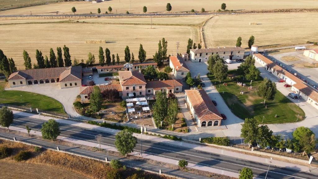 A residential area with multiple buildings, a curved road, and open fields.