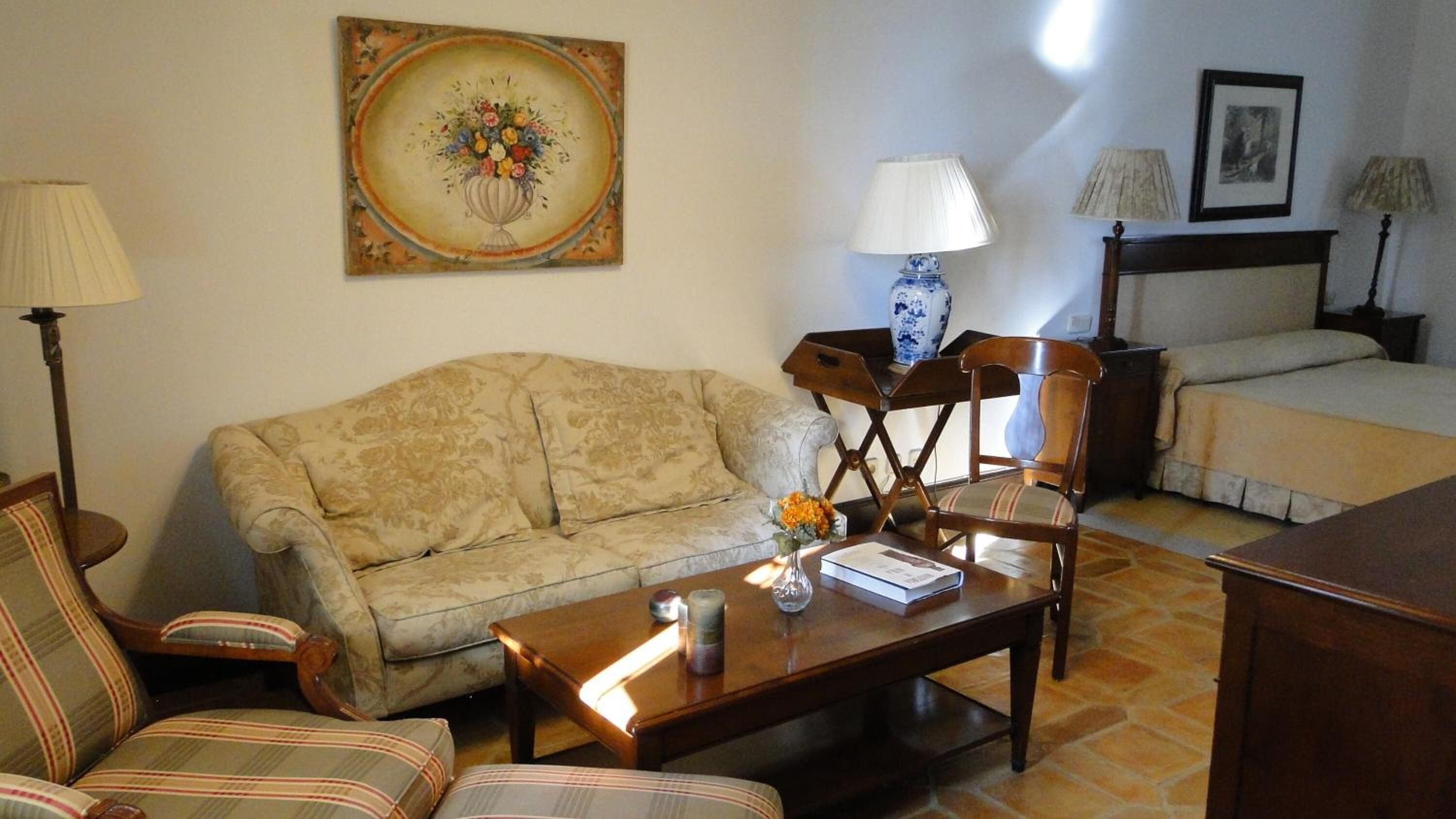 Un salon chaleureux avec un canapé, des fauteuils, une table basse et un tableau accroché au mur.