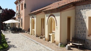 A cobblestone street with outdoor seating and a stone building with arches. - Hotel Vettonia (Ávila)