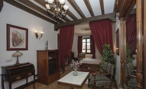 A traditional room with a wooden bed, a desk, a chair, and a large mirror. - Hotel Vettonia (Ávila)