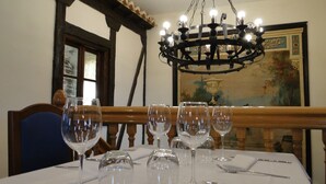 A dining table with multiple wine glasses and cutlery, a chandelier, and a painting on the wall. - Hotel Vettonia (Ávila)