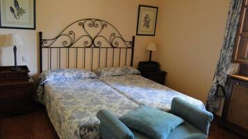 Een slaapkamer met een bed, twee nachtkastjes, een lamp en een stoel.