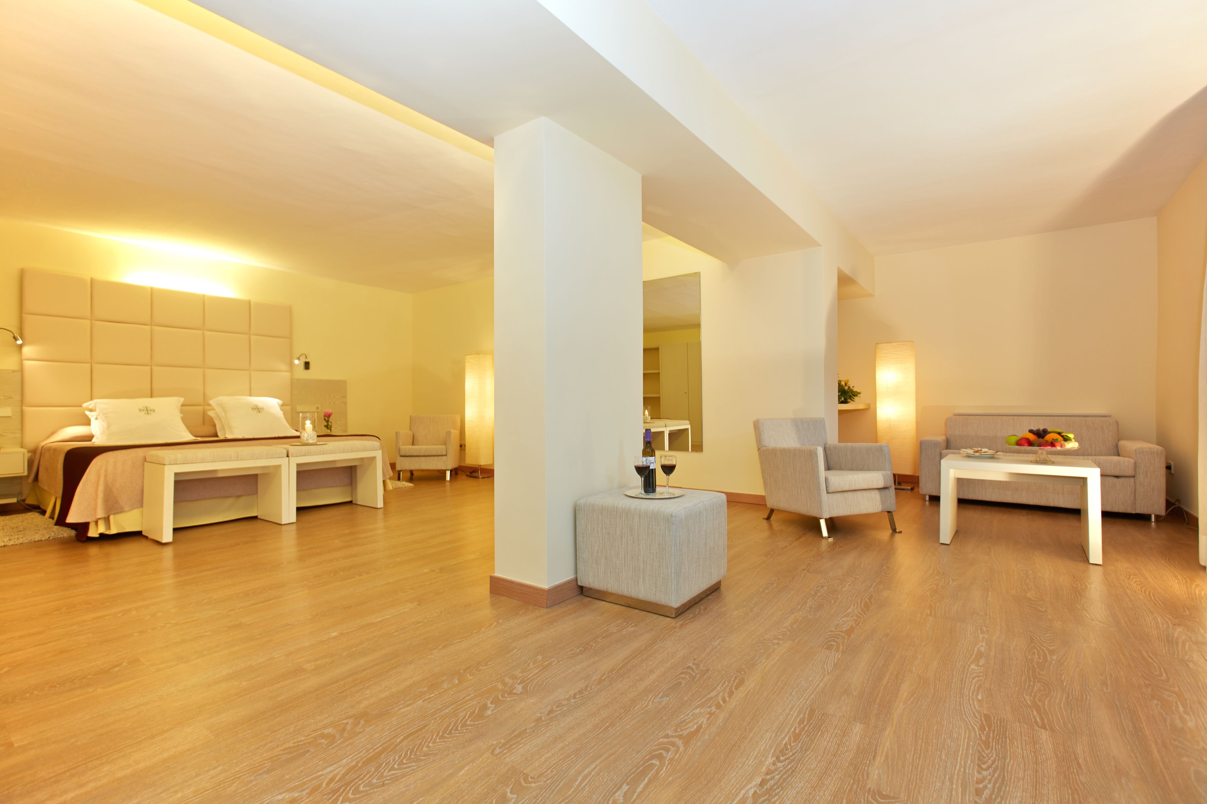 Una habitación de hotel moderna con una cama grande, un sofá, una mesa de centro y una mesita auxiliar.