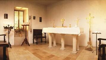 A church interior with a white altar, pews, and religious statues.