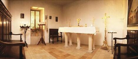 Ein Kircheninneres mit weißem Altar, Kirchenbänken und religiösen Statuen.