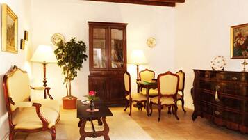 Un salón tradicional con muebles de madera, una planta en maceta y un aparador.