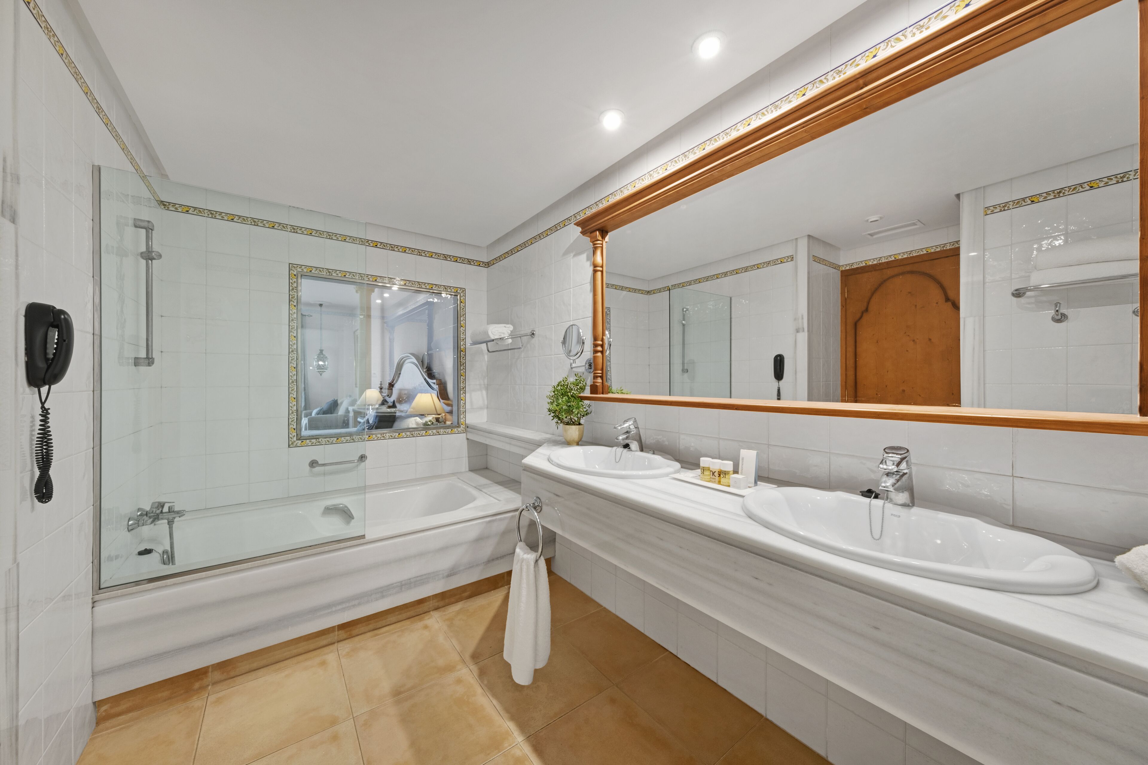 A modern bathroom with two sinks, a bathtub, and a large mirror.