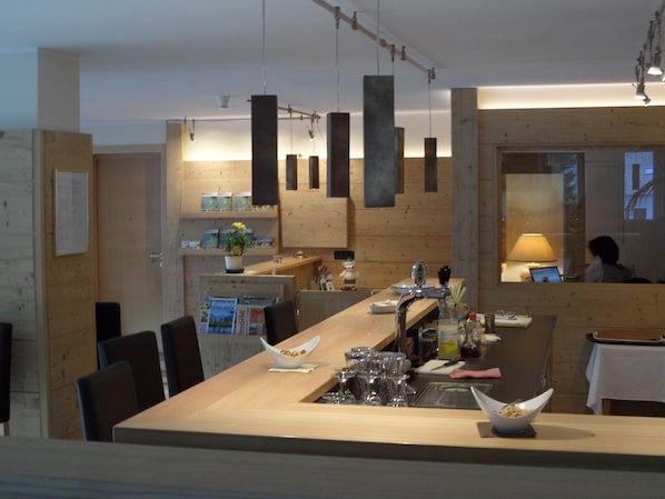A modern kitchen with wooden accents, a bar area, and a dining space with chairs.