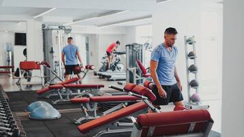 Gimnasio con equipo de ejercicio, una persona caminando y otra entrenando.
