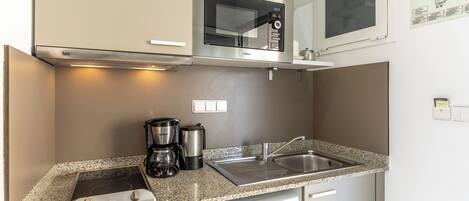 A compact kitchen with a microwave, coffee maker, and dishwasher.