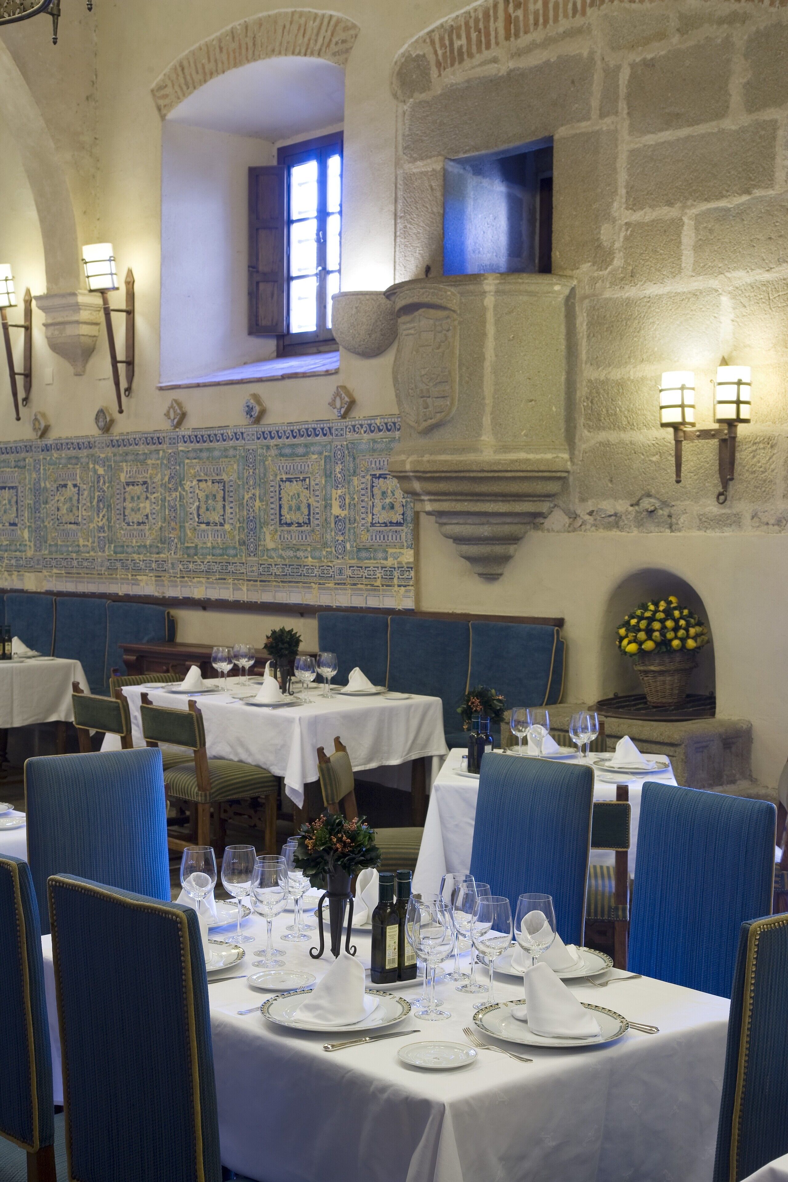 Een restaurant met gedekte tafels, blauwe gestoffeerde stoelen en witte tafellinnen.