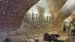 A cozy room with a stone ceiling, a cushioned bench, and a small table with candles. - Parador de Plasencia (Plasencia)