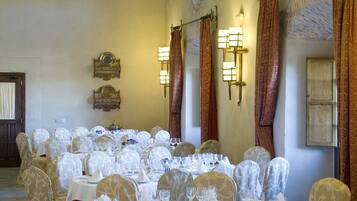 A banquet hall with round tables set for a formal event, featuring white tablecloths, floral centerpieces, and elegant chairs.