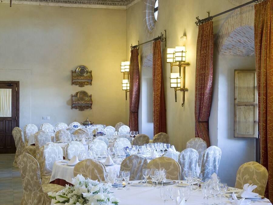 A banquet hall with round tables set for a formal event, featuring white tablecloths, floral centerpieces, and elegant chairs.