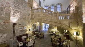 A historic building with a stone staircase, wooden furniture, and multiple levels. - Parador de Plasencia (Plasencia)