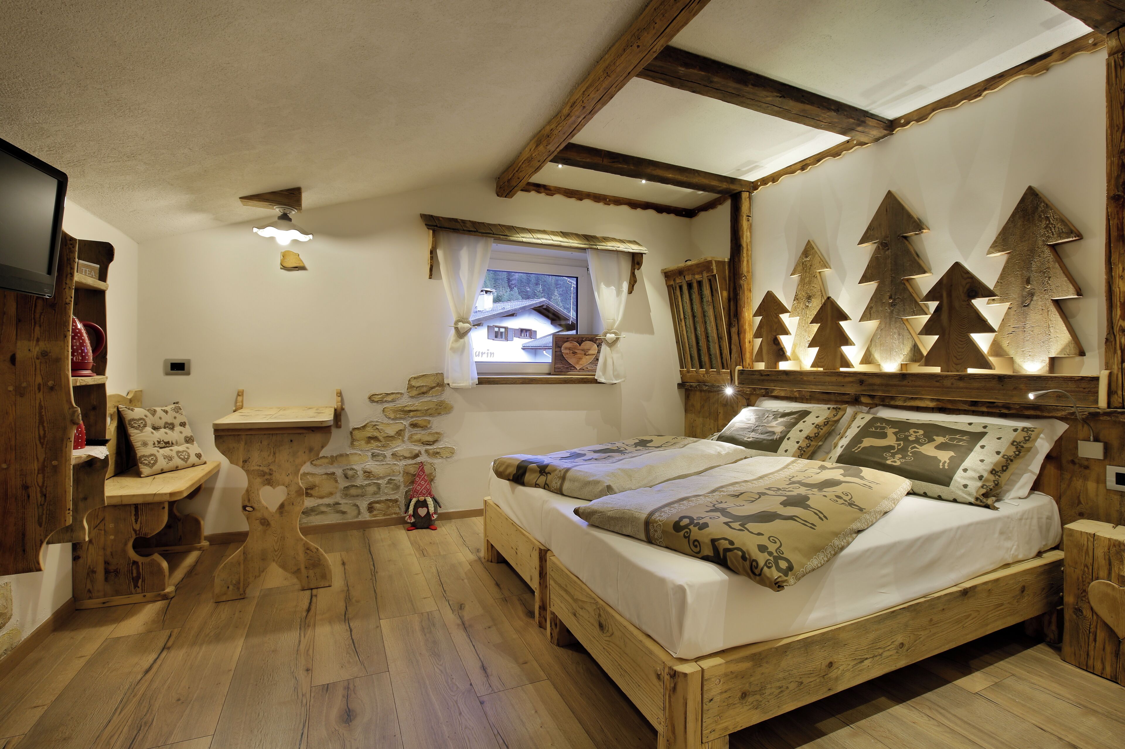 Una camera accogliente con un letto di legno, una finestra vista e un muro decorato con forme di alberi in legno.