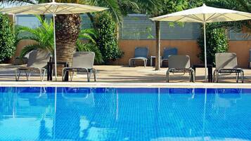 Una piscina al aire libre, sombrillas, tumbonas