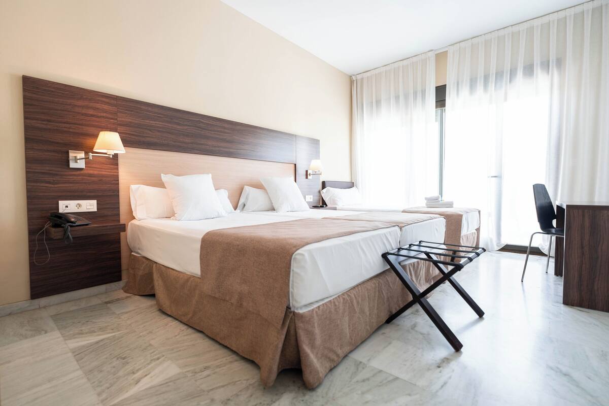 Una habitación de hotel moderna con una cama grande, mesitas de noche, un escritorio y una silla.