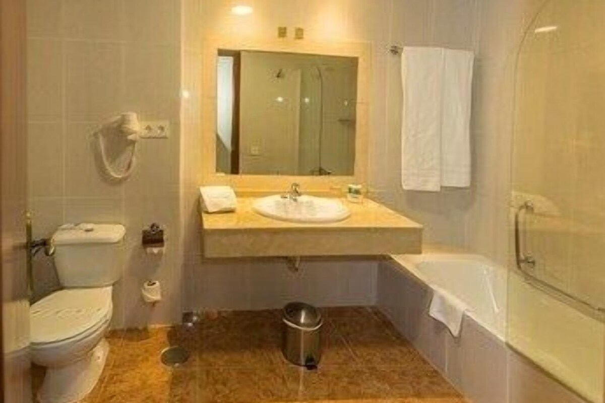 Une salle de bain équipée de toilettes, d’un lavabo, d’un miroir et d’une baignoire.
