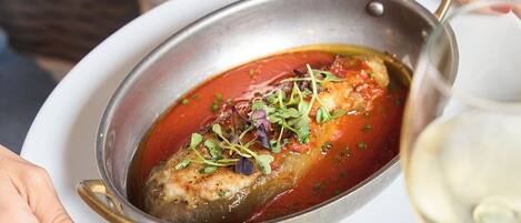 A dish with a red sauce, garnished with greens, served in a metal pan.