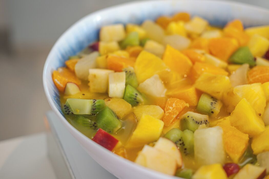 Un tazón de ensalada de frutas mixtas con kiwi, mango y naranja.
